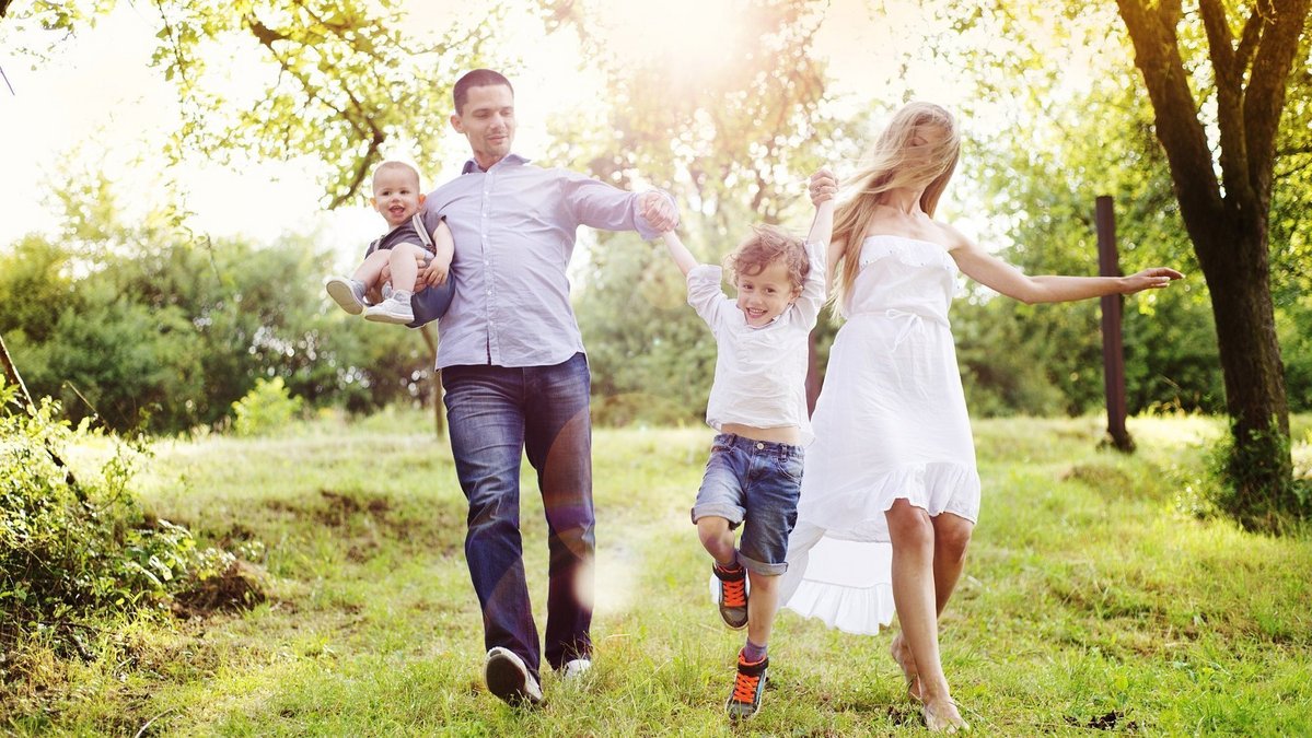 Familienfreundlich wohnen im Grünen Familie läuft gemeinsam durch grüne Natur in Blender