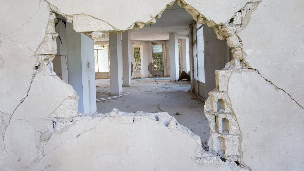 Großer Mauerdurchbruch in einer stark beschädigten Innenwand eines sanierungsbedürftigen Gebäudes