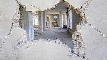 Großer Mauerdurchbruch in einer stark beschädigten Innenwand eines sanierungsbedürftigen Gebäudes