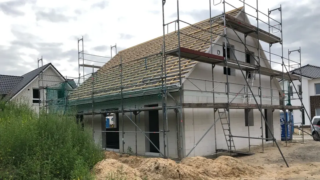 Einfamilienhaus im Rohbau mit Gerüst, Dachstuhl und Baugrundstück in Diepenau-Essern.