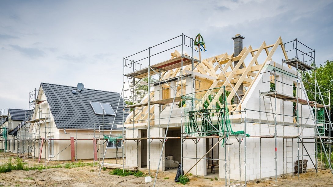 Rohbau eines Einfamilienhauses mit Dachstuhl Rohbau eines Einfamilienhauses mit Dachstuhl, Gerüst und Richtkranz als Symbol für den Hausbau mit Contura Bau GmbH