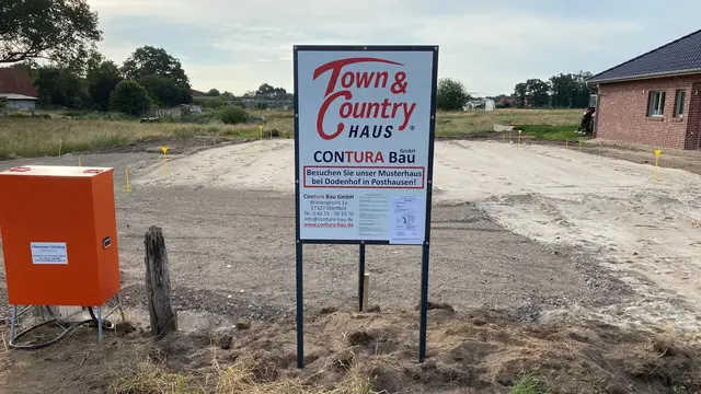 Baugrundstück in Diepenau-Essern mit Baustellenschild von Contura Bau GmbH und Town & Country Haus.