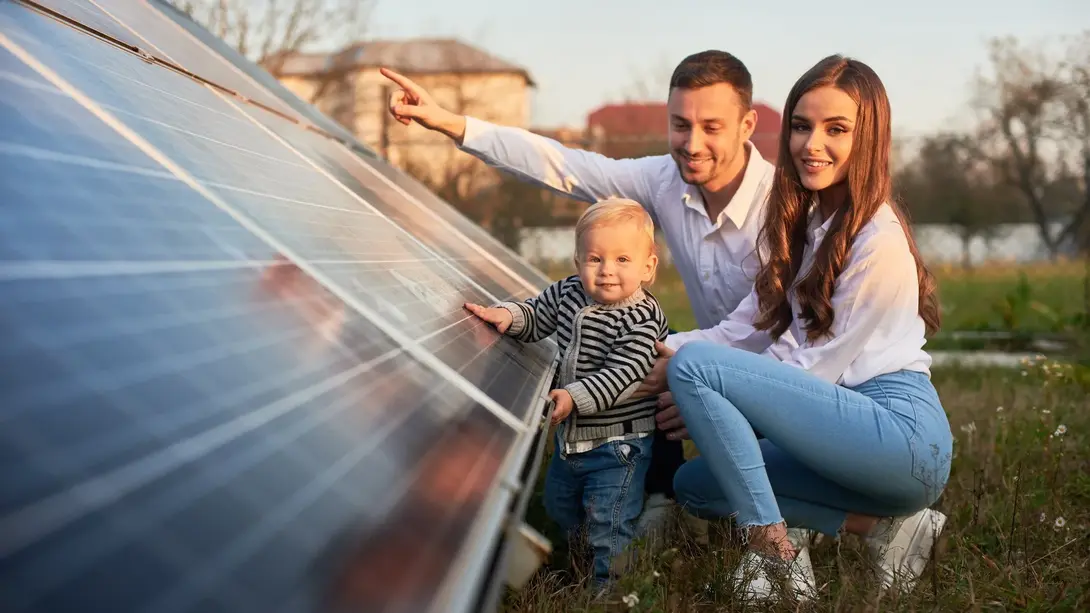 Junge Familie mit Kind betrachtet Photovoltaikmodule als Symbol für energieeffizienten Hausbau