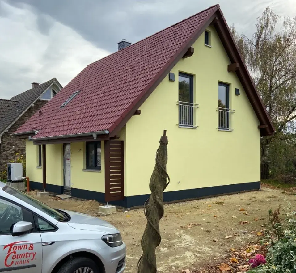 Massivhaus in Landesbergen bauen mit Contura Bau GmbH Fertiggestelltes Einfamilienhaus in Landesbergen mit rotem Satteldach und Town & Country Haus Fahrzeug