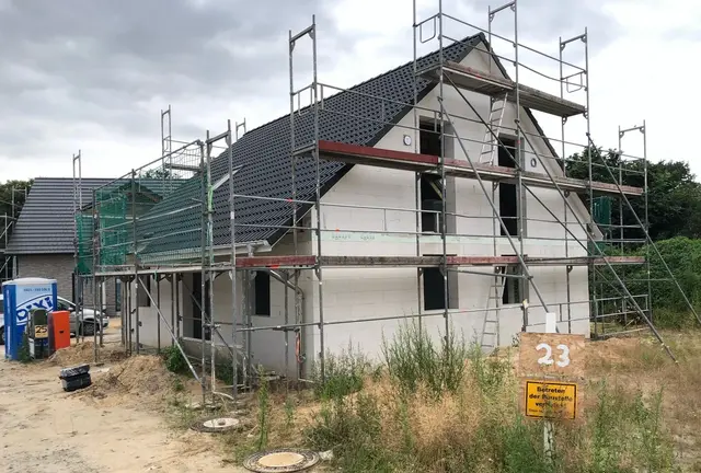 Hausbau in Diepenau im Rohbau Einfamilienhaus im Rohbau mit Gerüst, dunklem Satteldach und Baugrundstück in Diepenau.