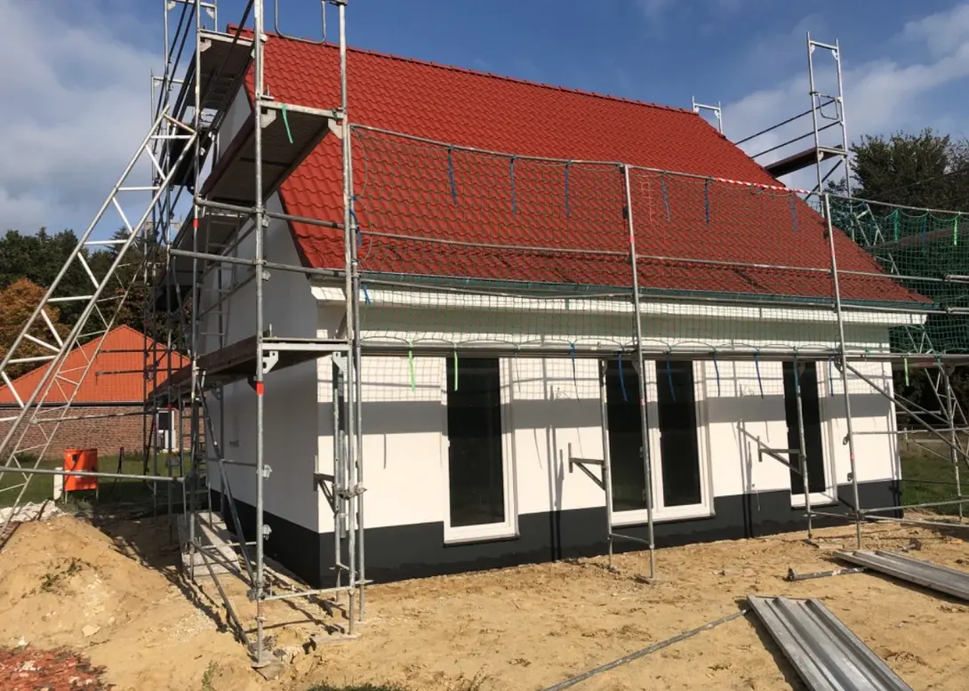 Einfamilienhaus im Bauprozess mit rotem Satteldach, Gerüst und vorbereiteter Fassade in Diepenau-Essern.