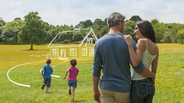 Familie plant ihr Traumhaus in Niedersachsen mit Contura Bau Paar steht mit Kindern auf einer grünen Wiese und blickt auf die Skizze ihres zukünftigen Hauses in Niedersachsen