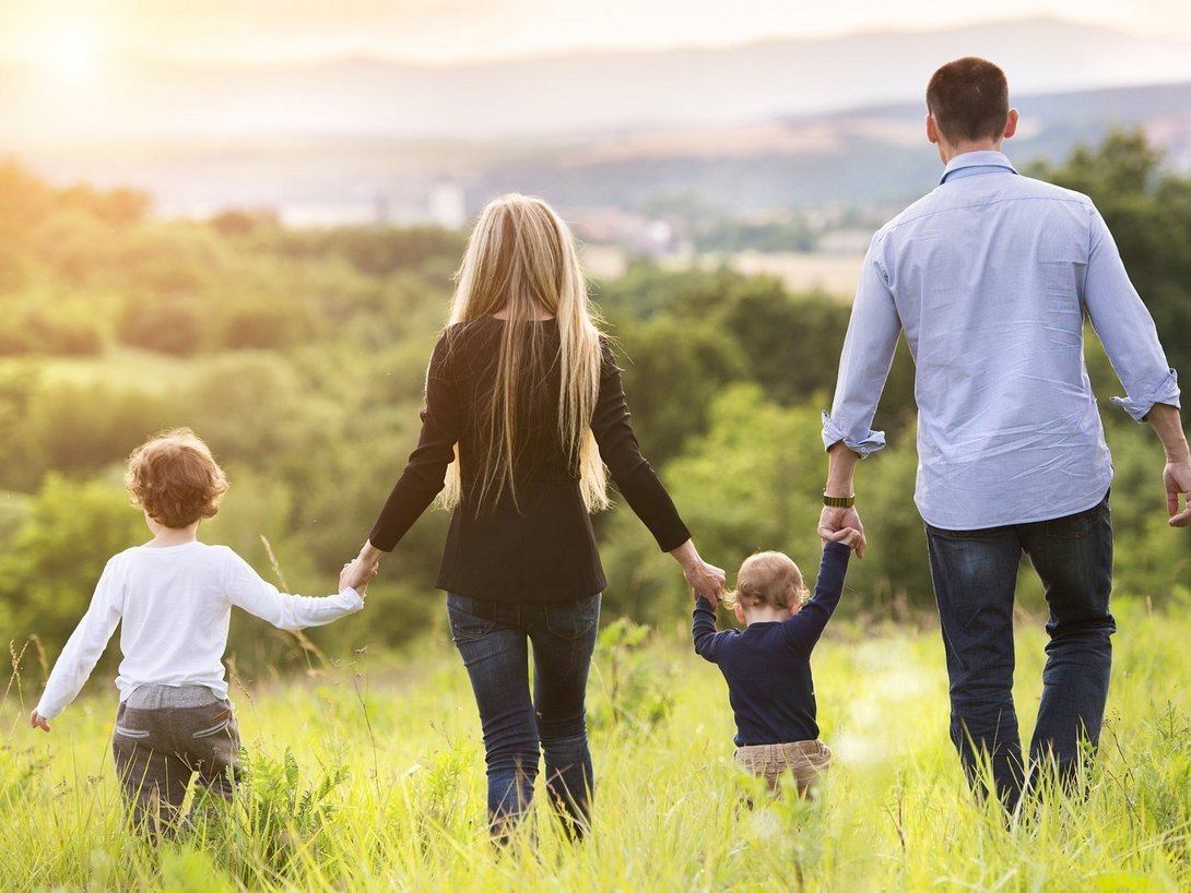 Familie mit zwei Kindern geht gemeinsam über eine Wiese als Symbol für familienfreundliches Wohnen und den Hausbau mit Contura Bau GmbH