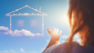Der Traum vom eigenen Zuhause Person blickt auf eine Hausform aus Wolken am Himmel