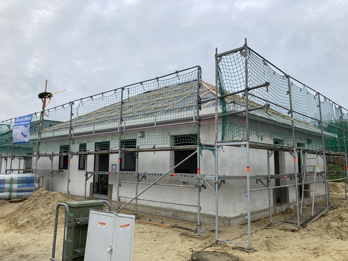 Rohbau eines Einfamilienhauses mit Gerüst auf einer Baustelle