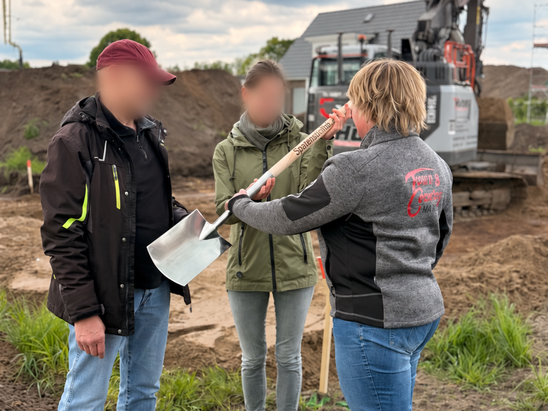 Bauherren beim Spatenstich für den Bungalow 131 in Etelsen-Langwedel mit einer Mitarbeiterin von Contura Bau auf dem Baugrundstück