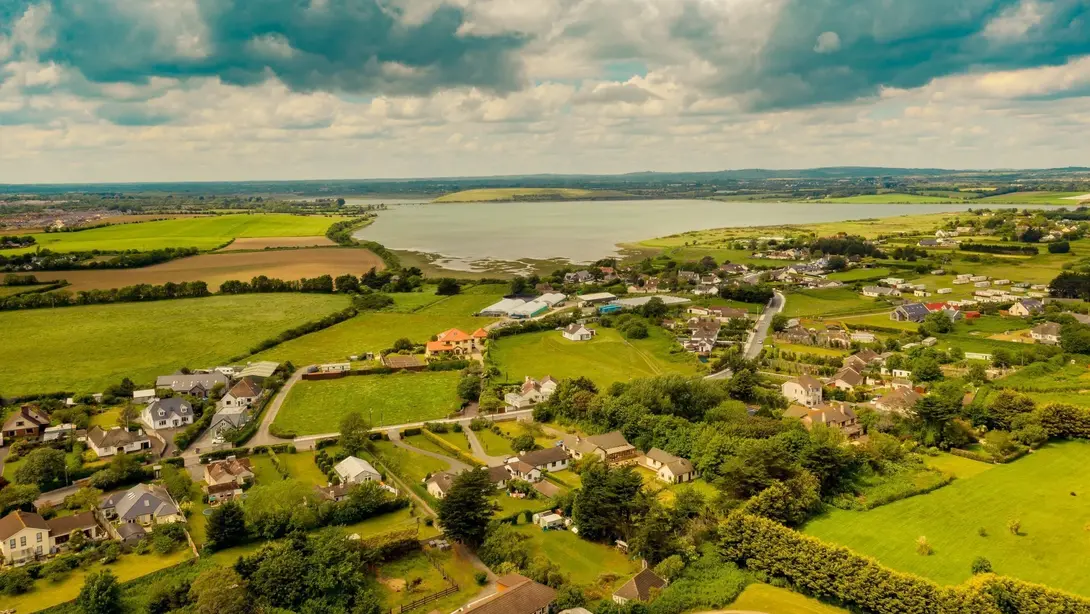 Naturnahes Wohnen in Pennigsehl mit Blick auf die Umgebung Luftaufnahme einer grünen Landschaft mit Wohngebiet, Feldern und Wasserfläche als Symbol für naturnahes Wohnen in Pennigsehl.