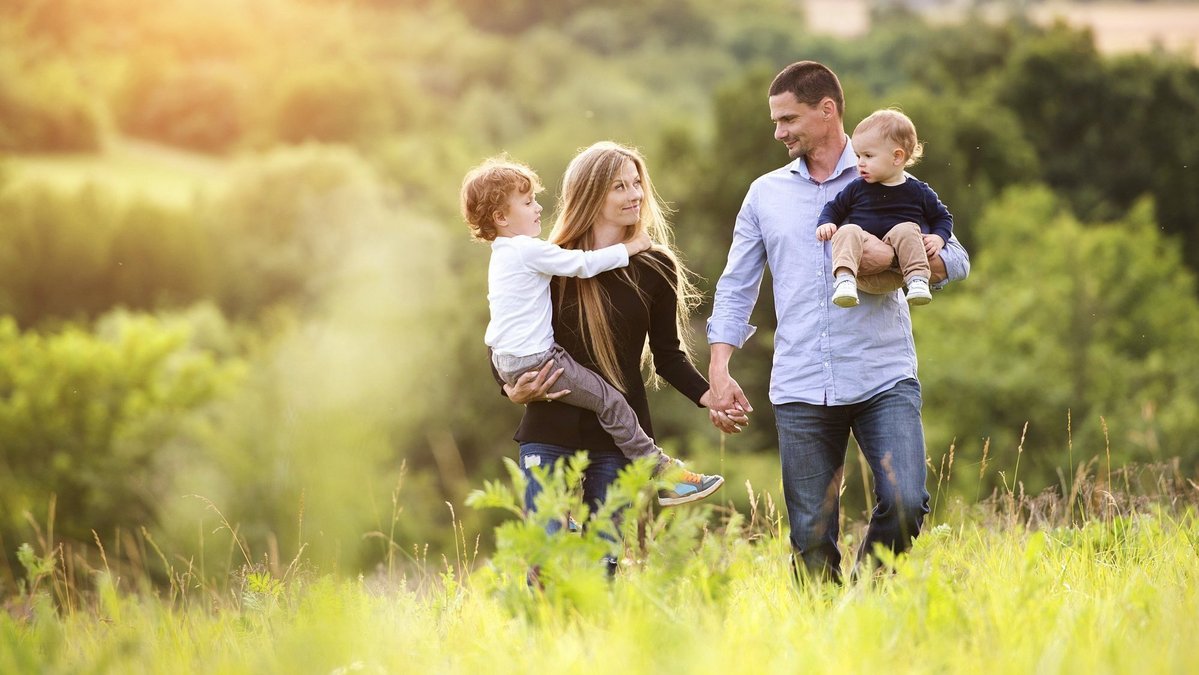 Familie spaziert bei Sonnenuntergang durch eine grüne Landschaft in Essern
