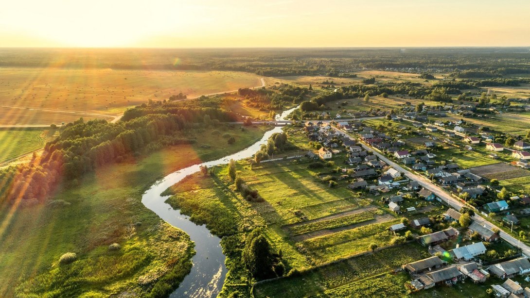 Luftaufnahme einer ländlichen Wohnlage mit Fluss und Sonnenuntergang