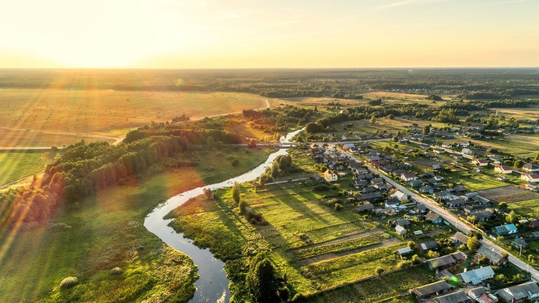 Naturnah wohnen in Lichtenhorst-Ortsmitte Luftaufnahme einer ländlichen Ortschaft mit Flusslauf und grüner Landschaft als Symbol für naturnahes Wohnen in Lichtenhorst-Ortsmitte mit Contura Bau GmbH