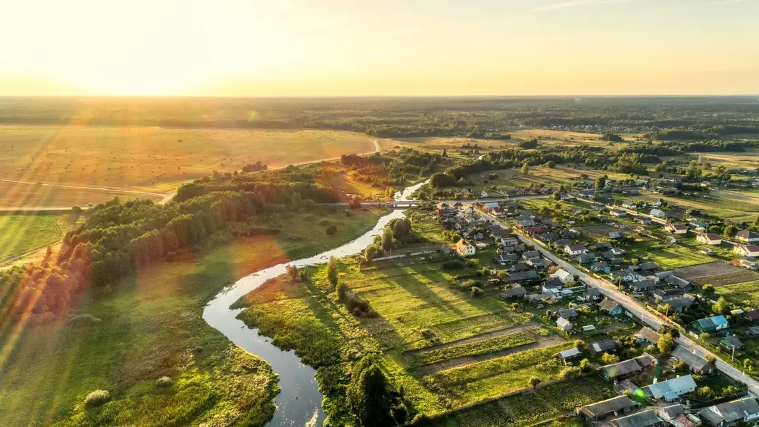 Luftaufnahme einer ländlichen Ortschaft mit Flusslauf und grüner Landschaft als Symbol für naturnahes Wohnen in Lichtenhorst-Ortsmitte mit Contura Bau GmbH