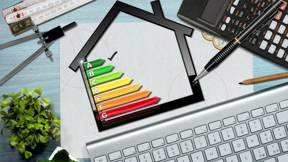 Energieeffizienz-Symbol eines Hauses mit Planungsunterlagen, Taschenrechner und Tastatur