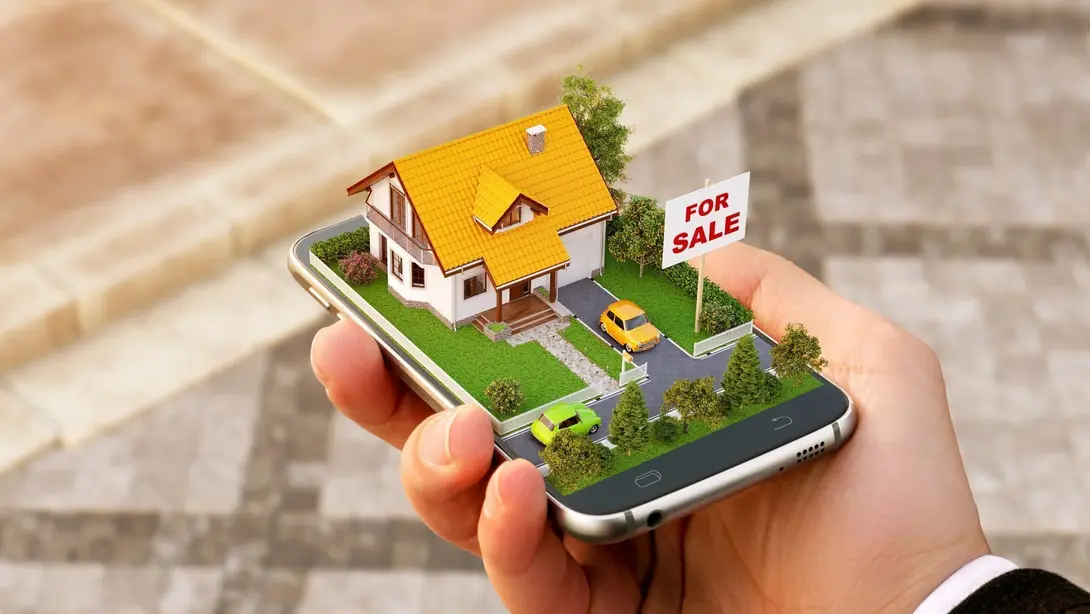 Grundstücks- und Immobiliensuche online Hand hält ein Smartphone mit visualisiertem Einfamilienhaus und Verkaufsschild