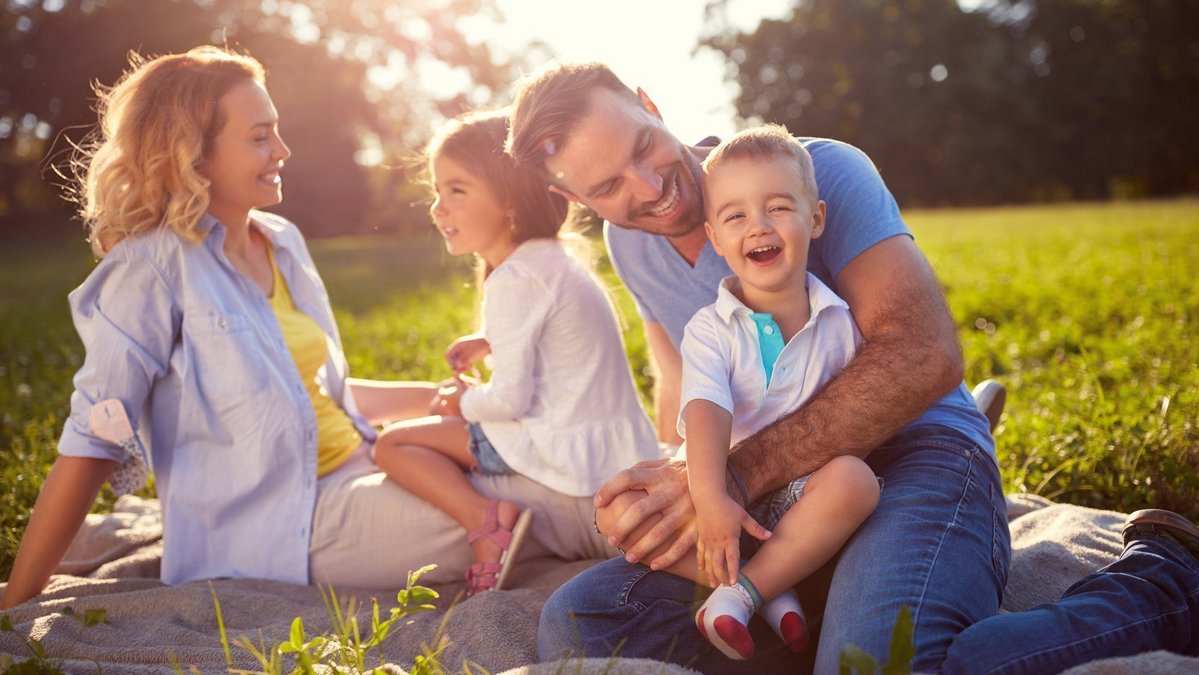 Familienleben und Wohnen im Grünen in Stolzenau Familie sitzt lachend auf einer Wiese im Grünen als Symbol für familienfreundliches Wohnen und Lebensqualität in Stolzenau.