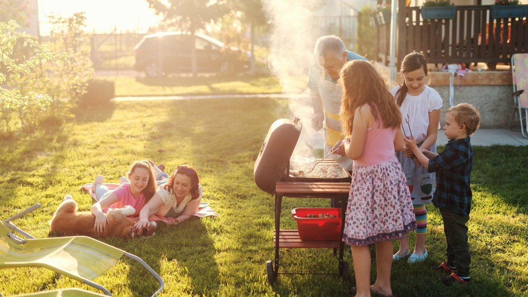Familie und Kinder verbringen gemeinsam Zeit im Garten beim Grillen als Symbol für familienfreundliches Wohnen in Bassum-Neubruchhausen mit Contura Bau GmbH
