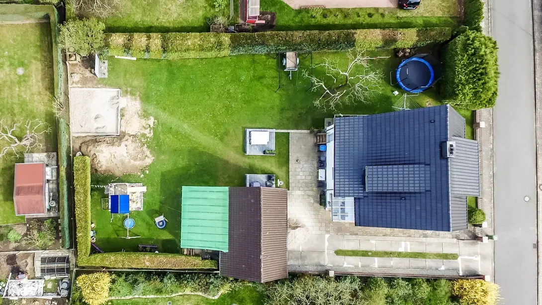 Einfamilienhaus mit großem Grundstück aus der Luft Luftaufnahme eines Einfamilienhauses mit großem Garten, Terrasse und Grundstück als Beispiel für Grundstücksnutzung und Hausbau mit Contura Bau GmbH