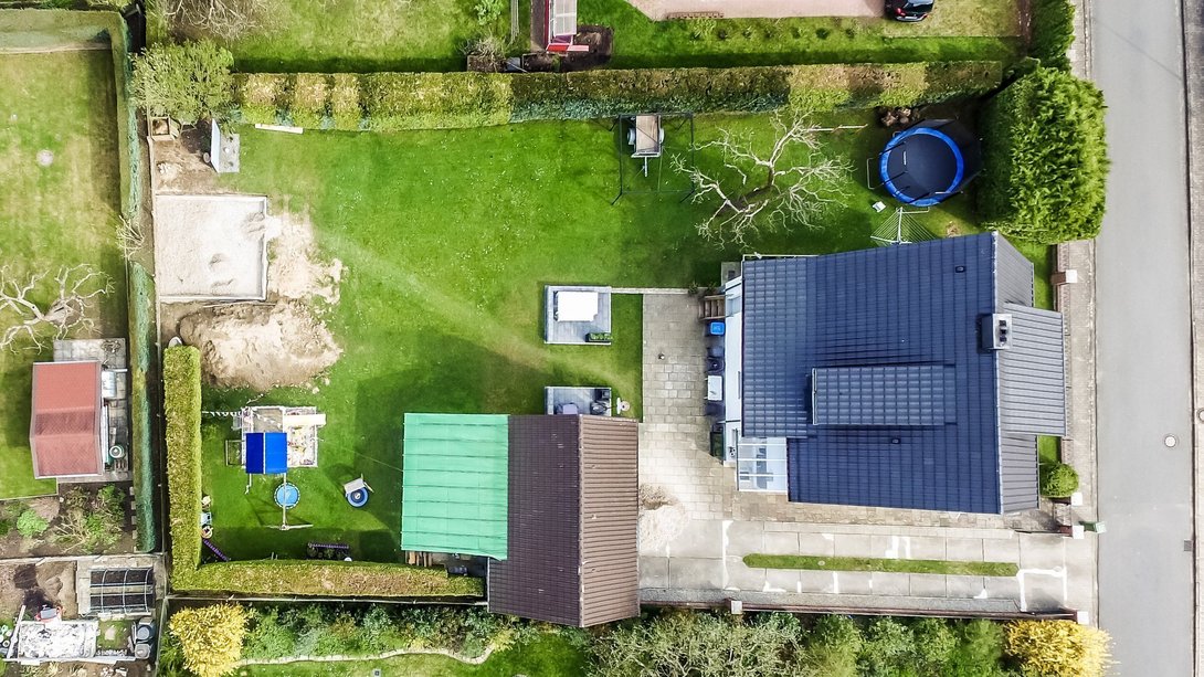 Luftaufnahme eines Einfamilienhauses mit großem Garten, Terrasse und Grundstück als Beispiel für Grundstücksnutzung und Hausbau mit Contura Bau GmbH