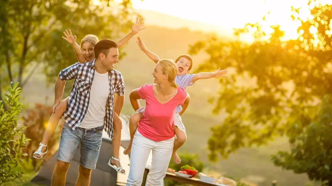 Familie mit zwei Kindern genießt gemeinsame Zeit in sonniger, naturnaher Umgebung