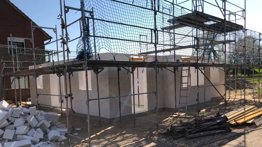 Einfamilienhaus im Rohbau mit Gerüst, gemauerten Außenwänden und Baustellenmaterial in Bruchhausen-Vilsen.