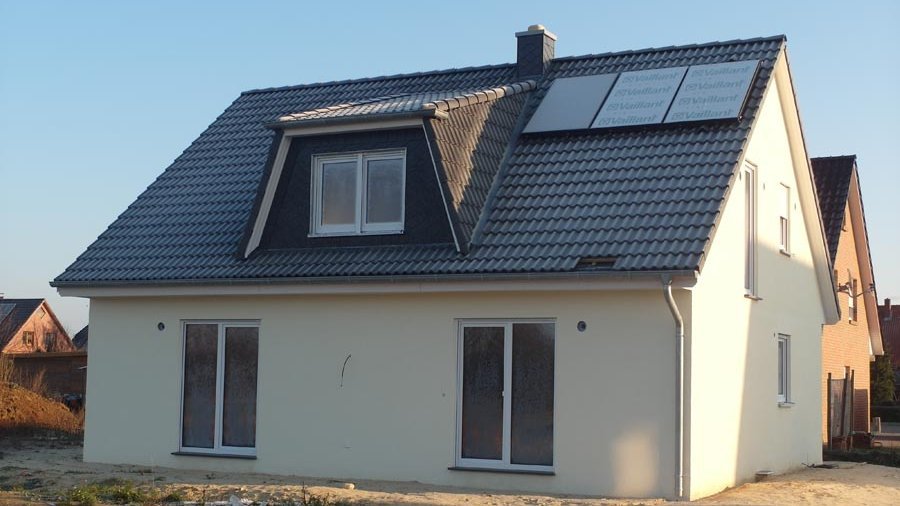 Einfamilienhaus mit Satteldach und Solarmodulen in Stolzenau Einfamilienhaus mit heller Fassade, dunklem Satteldach, Dachgaube und Solarmodulen in einem Wohngebiet in Stolzenau.