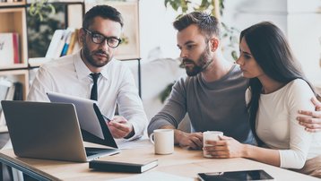 Beratungsgespräch zu Versicherungen beim Hausbau mit Bauherren und Berater am Laptop