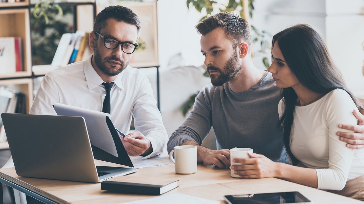 Beratungsgespräch zu Versicherungen beim Hausbau mit Bauherren und Berater am Laptop
