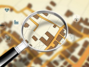 Grundstückssuche auf einem digitalen Lageplan Lupe über einem digitalen Lageplan mit markiertem Grundstück