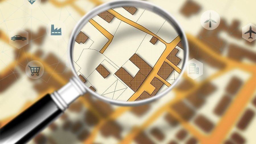 Grundstückssuche und Standortprüfung in Leese Lupe über einem Lageplan als Symbol für Grundstückssuche, Standortprüfung und Hausbauplanung in Leese mit Contura Bau GmbH